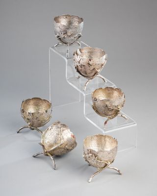 four silver bowls are stacked on a clear stand on a gray background