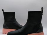 un gros plan sur une paire de bottes noires à semelles roses