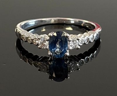 an image of a blue sapphire and diamond ring on a black surface