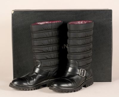une paire de bottes en cuir noir avec une doublure rouge, posée devant une boîte noire