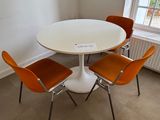 une table blanche entourée de quatre chaises orange