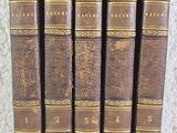 six antique books lined up in a row on top of a table