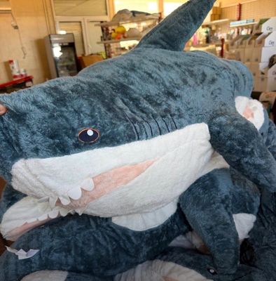 un gros requin en peluche posé par terre