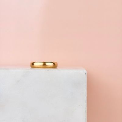 un gros plan d'une alliance en or posée sur une boîte blanche