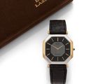 a close up of a black and gold wrist watch next to a book