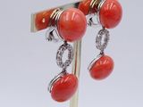 pair of red coral and diamond earrings on a gold plated stand