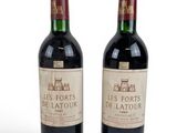 two bottles of red wine sitting next to each other on a white surface