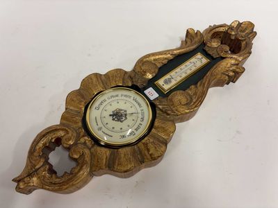 une horloge dorée posée sur une table blanche, avec une horloge au milieu