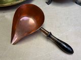 a copper spoon with a black handle sitting on a table