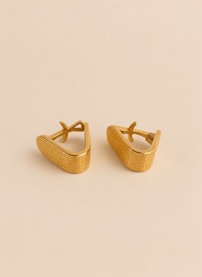 une paire de boucles d'oreilles en or sur un fond beige