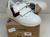 des baskets blanches et bordeaux à velcro, posées sur une boîte en carton
