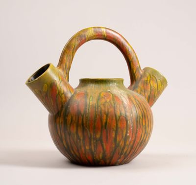 an orange and green teapot with a handle on a white surface