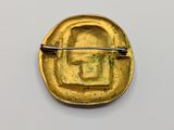 a close up of a gold brooch with a pin in the middle