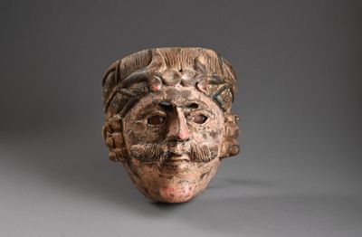 une image représentant un masque en argile sur fond gris