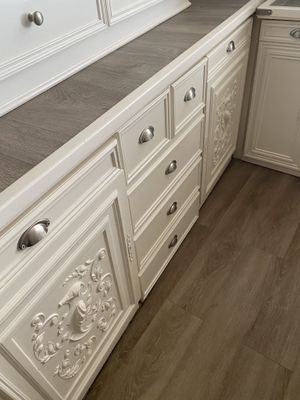 a kitchen with white cabinets and wood floors in it