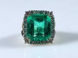 a close up of a ring with a green stone surrounded by diamonds