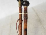two wooden canes with black handles on a white surface
