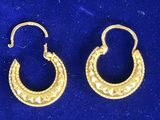 une paire de boucles d'oreilles créoles en or sur fond bleu