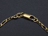 a close up of a gold chain bracelet on a black surface