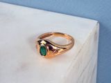 gros plan d'une bague en or avec une pierre verte