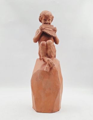 statue d'un garçon jouant de la flûte sur un rocher