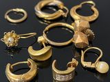 plusieurs paires de boucles d'oreilles et de bagues en or posées sur un fond noir