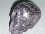 a purple crystal skull sitting on a white surface