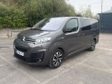 Une camionnette Citroën garée sur un parking, avec des arbres et des buissons en arrière-plan
