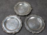 trois assiettes en argent ornées de motifs, posées sur une table