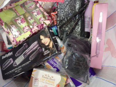 a pile of hair products that are on a bed