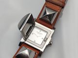 gros plan d'une montre sur une surface blanche avec un bracelet marron
