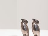 deux oiseaux en argent posés l'un à côté de l'autre sur une table blanche