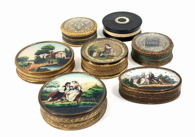 plusieurs petites boîtes rondes ornées de peintures, posées sur une surface blanche