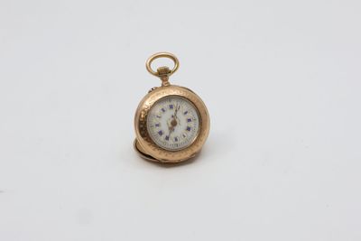 une vieille montre de poche en or avec un cadran blanc posée sur une surface blanche