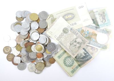 une pile de billets et de pièces posée sur une surface blanche