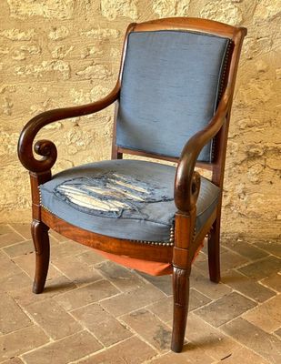 une chaise en bois avec une assise rembourrée bleue, posée sur un sol en briques