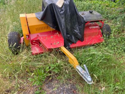 une tondeuse à gazon recouverte d'une housse, posée dans l'herbe