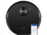 un aspirateur robot noir avec un téléphone à côté