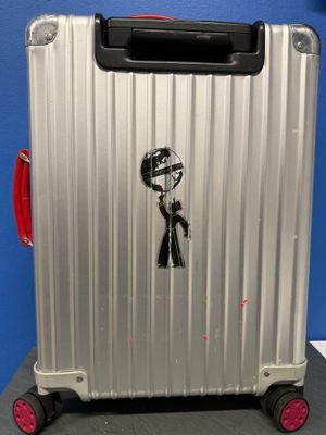 une valise argentée sur laquelle est collé un autocollant représentant un homme