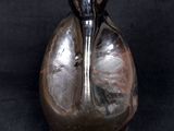 a silver vase with a black handle sitting on a black surface