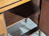 a wooden cabinet that has a drawer underneath it