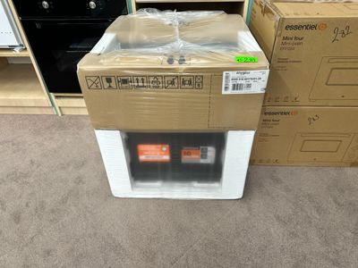 un réfrigérateur blanc posé à même le sol, à côté d'une pile de cartons