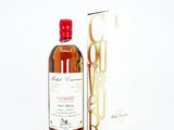 une bouteille d'alcool posée à côté d'une boîte sur une surface blanche