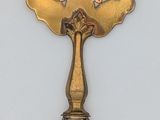 a silver spoon with a gold handle on a white surface