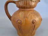 a brown vase with a handle on a white table