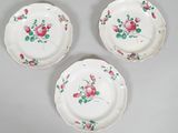 three plates with pink flowers on them sitting on a table