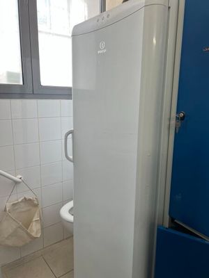 un réfrigérateur blanc dans une salle de bains, à côté d'une porte bleue