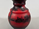 a red vase with a black design on it
