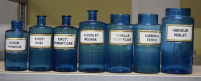 de nombreuses bouteilles bleues munies d'étiquettes, posées sur une étagère