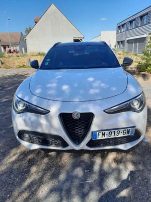 a white alfa car parked in front of a house